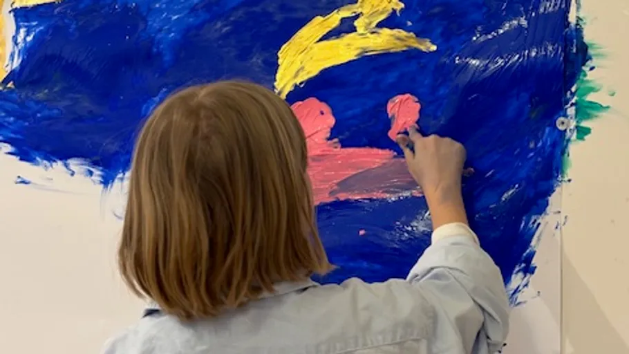 Child painting abstract image on wall.