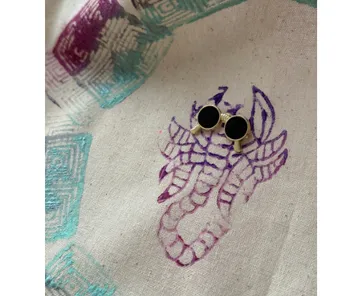 Small binoculars on fabric with scorpion print.