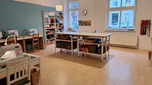 Sewing room with tables and shelves, bright interior.