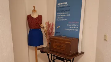 Mannequin next to banner and sewing box.