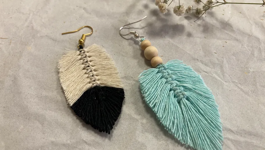 Zwei handgemachte Makramee-Ohrringe auf Papierhintergrund.