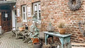 Dekorierte Ziegelterrasse mit Stühlen und Pflanzen.