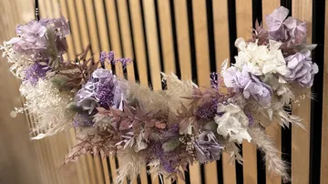 Decorative flower wreath hanging on wooden slats.