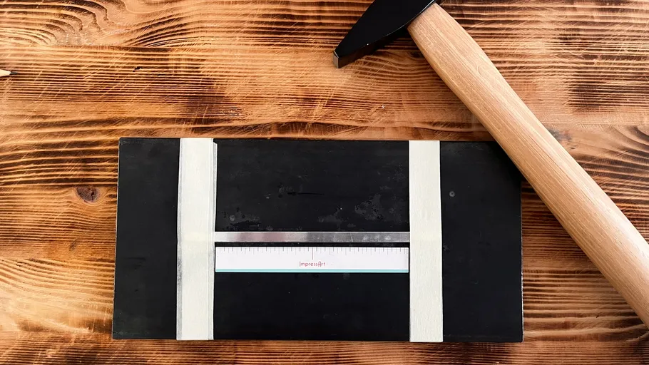 Hammer and metal block on wooden surface.