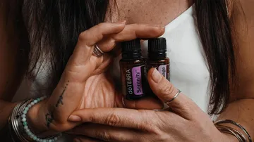 Hands holding essential oil bottles, close-up.