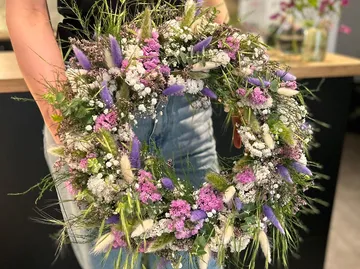 Person holding floral wreath indoors.