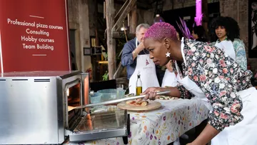 Frau überprüft Pizza im Ofen.