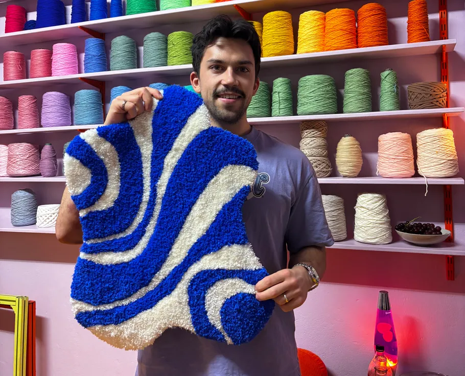 Person holding blue and white rug in thread shop.