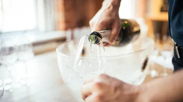 Person pouring wine into glass, blurred background.