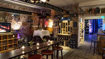 Cozy wine cellar with wooden furniture and bottles.