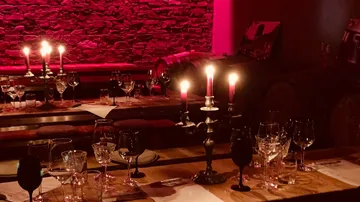 Kerzenbeleuchtetes Tischgedeck in rustikalem Weinkeller.