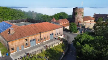 Burg mit Turm und Nebengebäuden in der Natur.