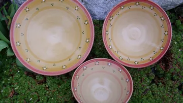 Drei Keramikschalen mit Blumenmustern auf Gras.