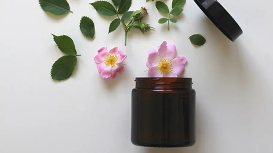 Open jar with flowers and leaves nearby.