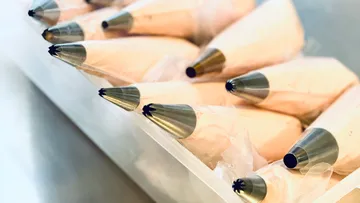 Piping bags filled with cream, in container.