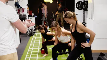 Menschen trainieren im Fitnessstudio auf grünem Weg.
