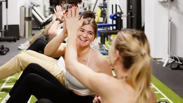 Zwei Frauen geben sich High-Five im Fitnessstudio.