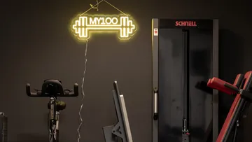 Neonschild "MY100" über Fitnessgeräten.