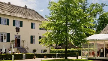 Großes Haus mit Außensitzbereich, sonniger Tag.
