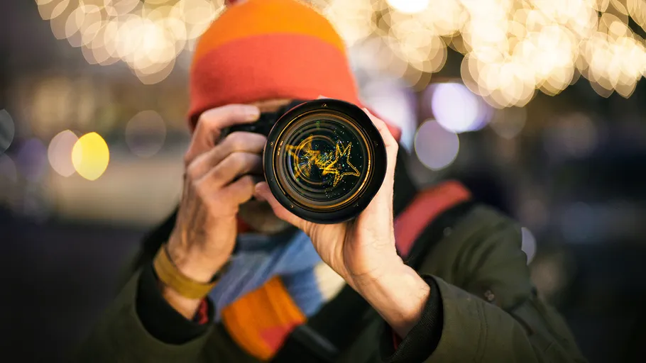 Person photographing with camera in festive lights.