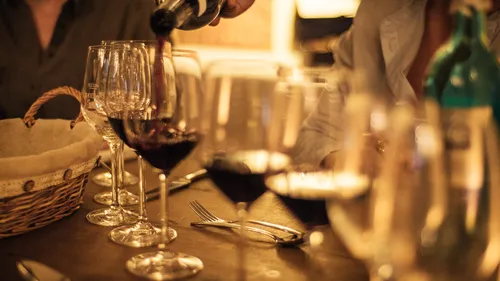 Wein wird in Gläser auf Tisch eingeschenkt.