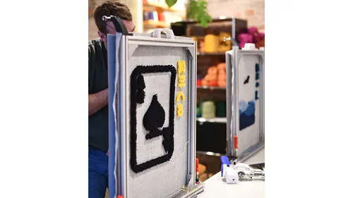 Person tuftet schwarzen Pik auf grauem Stoff.