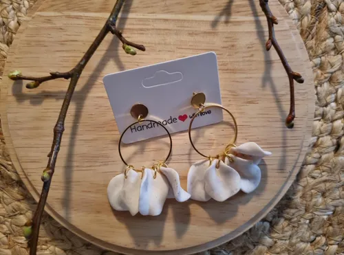 White petal earrings on wooden surface.