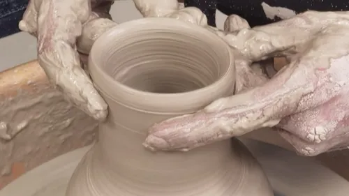 Hands shaping pottery on a wheel.