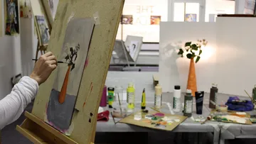 Person painting still life in art studio.