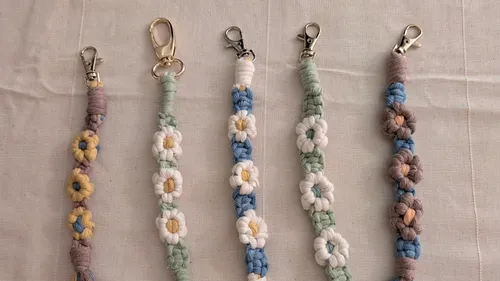 Fünf geflochtene Schlüsselanhänger mit Blumenmuster auf Stoff.