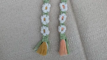 Geflochtene Bänder mit weißen Blumen auf Stoff.
