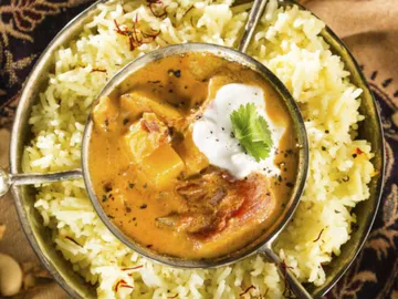 Rice and curry in a bowl, on a decorative surface.