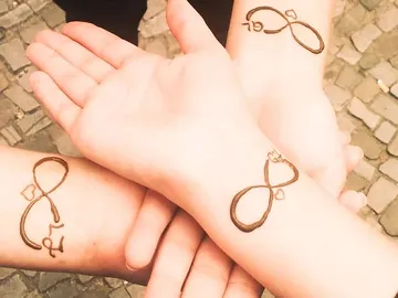 Drei Hände zeigen Henna-Designs im Freien auf Steinboden.