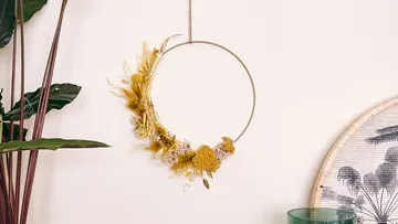 Blumenkranz-Deko hängt an einer Wand.