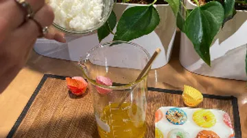 Hand fügt Zutat in Becher auf Tisch hinzu.