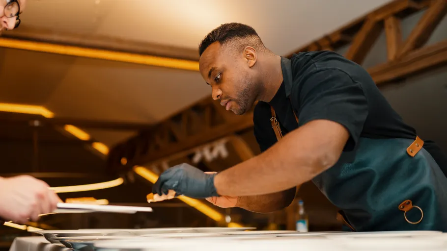 Koch richtet Essen an Restauranttresen an.