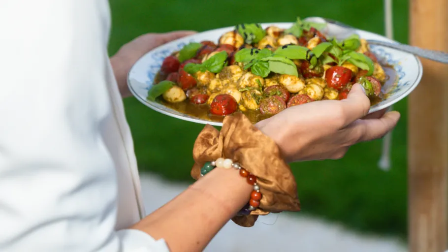 Person hält Salatteller mit Tomaten im Freien.