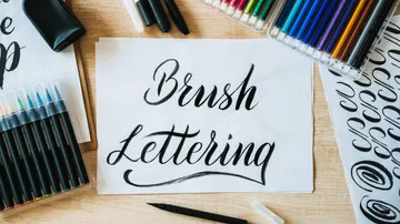 Brush lettering with colorful pens on table.