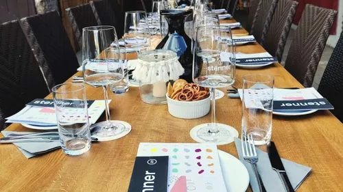 Long table set with glasses and menus outdoors.