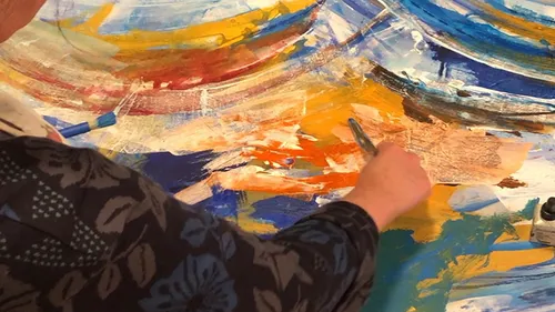 Person malt abstraktes Kunstwerk mit lebhaften Farben.