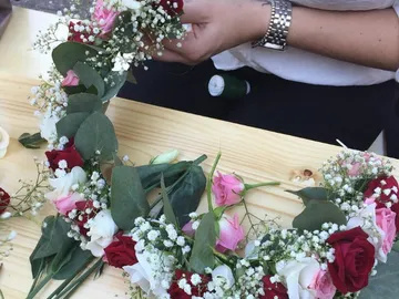 A wreath of flowers is tied on a wooden table.