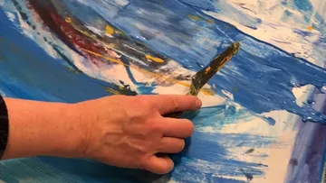 Hand benutzt Malmesser auf abstraktem Gemälde.