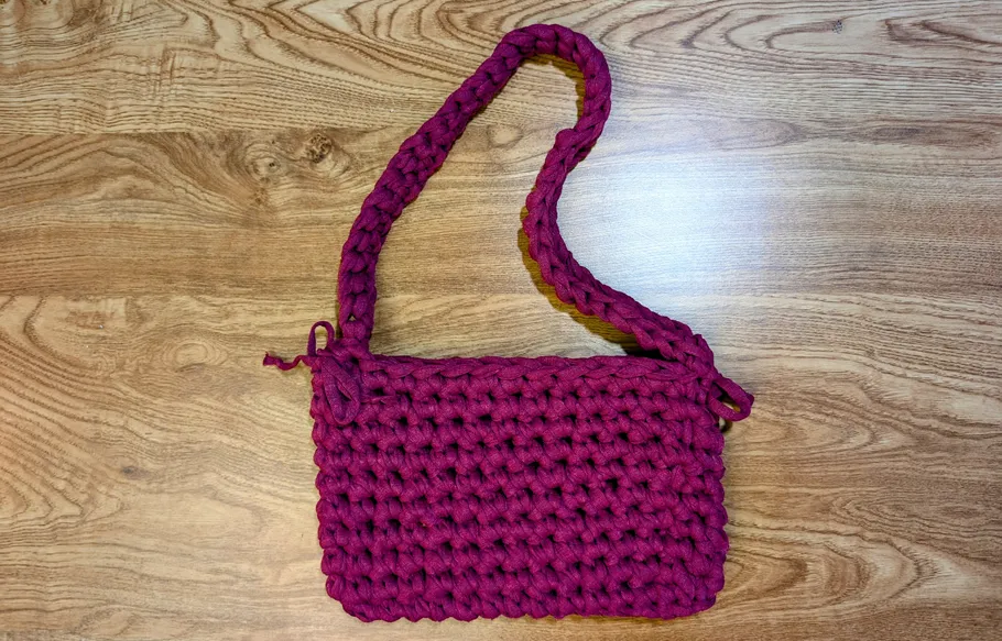 Rote gehäkelte Tasche auf Holzoberfläche.