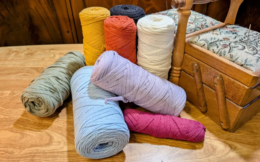 Colorful yarn spools on a wooden table.