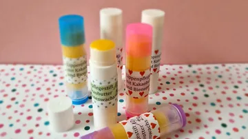 Bunte Lippenbalsam-Stifte auf gemustertem Untergrund.