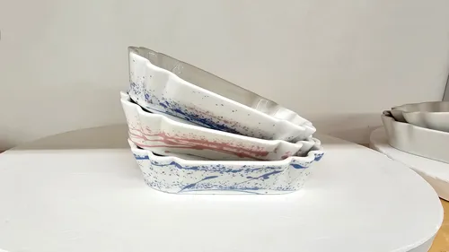 Three stacked ceramic dishes with colored splatters.