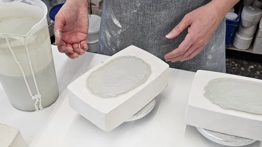 Person preparing ceramic molds on a table.