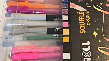 Bunte Stifte neben glänzender Verpackung.
