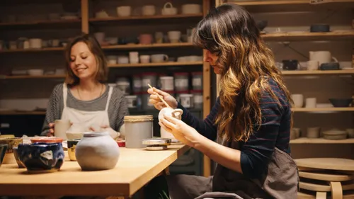 Two women crafting pottery in a workshop.