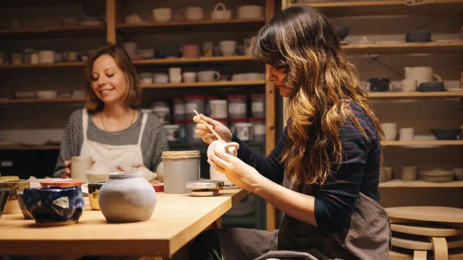 Zwei Frauen töpfern in einer Werkstatt.